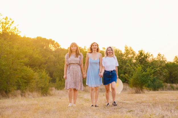 Photo a group of girlfriends jumps and runs outdoors a group of female friends hugs and enjoys the sunset in nature laughter smiles and joy