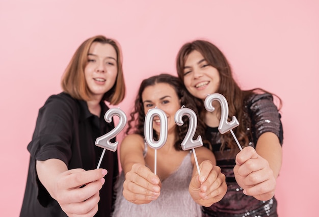 Photo a group of girlfriends on a pink background are holding the numbers 2022, new years celebration, christmas party.
