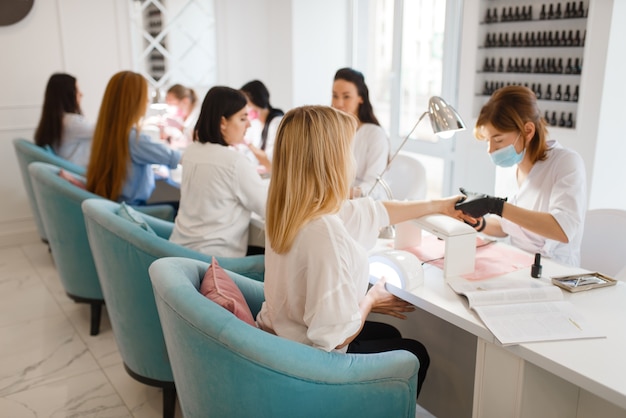 Group of girlfriends relax on manicure procedure in beauty salon.