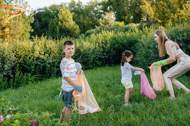 A group of girls with children at sunset are engaged in garbage collection in the park. Environmental care, recycling.