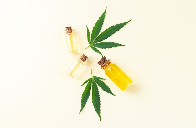 Group of glass bottles with cannabis cbd oil, thc tincture and hemp leaves. Top view, flat lay