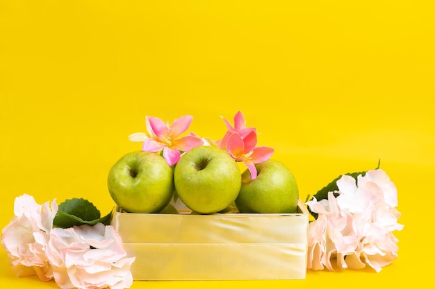 Group of green apples in wooden box on yellow background