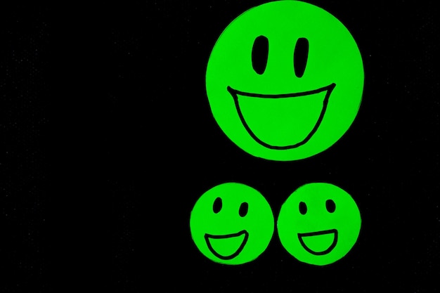 Group of green paper cut smile face on black background positive thinking mental health assessment world mental health day concept