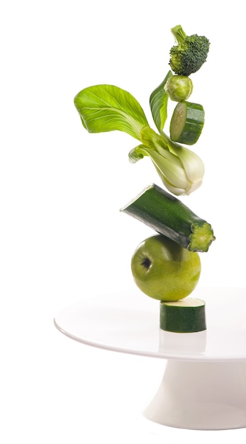 Group of green vegetables and fruits on white surface