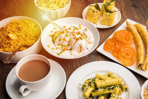 Photo group of gujarati snacks like jalebi-fafda, thepla, khaman dhokla, aloo bhujiya, khandvi,khakra, dahi vada, gathiya with hot tea