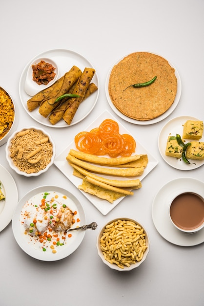 Group of Gujarati snacks like jalebi-fafda, thepla, khaman dhokla, aloo bhujiya, khandvi,khakra, dahi vada, gathiya with hot tea