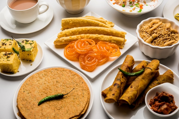 Группа гуджаратских закусок, таких как джалеби-фафда, тхепла, хаман дхокла, алоо бхуджия, кхандви, хакра, дахи вада, гатхия с горячим чаем.