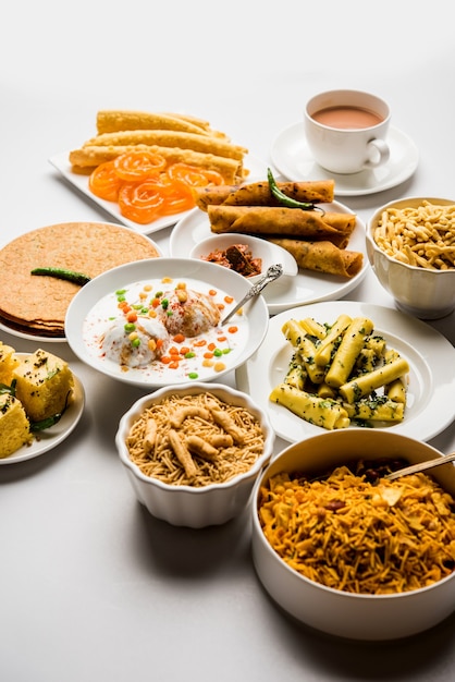 Foto gruppo di snack gujarati come jalebi-fafda, thepla, khaman dhokla, aloo bhujiya, khandvi,khakra, dahi vada, gathiya con tè caldo