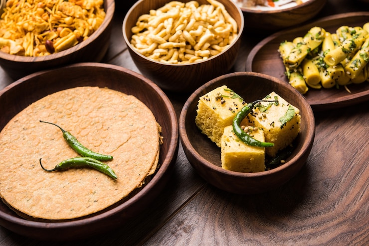 Photo group of gujarati snacks like jalebi-fafda, thepla, khaman dhokla, aloo bhujiya, khandvi,khakra, dahi vada, gathiya with hot tea