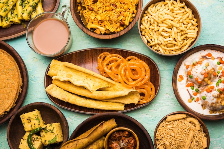 Photo group of gujarati snacks like jalebi-fafda, thepla, khaman dhokla, aloo bhujiya, khandvi,khakra, dahi vada, gathiya with hot tea