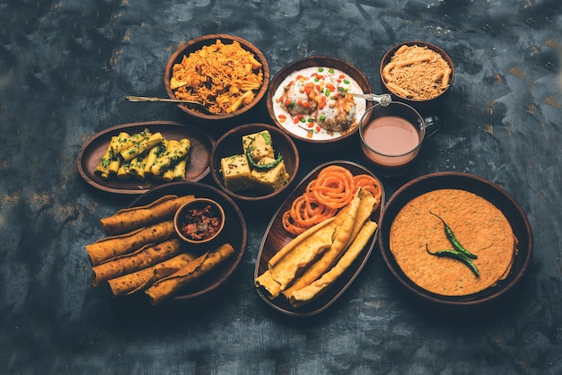 Photo group of gujarati snacks like jalebi-fafda, thepla, khaman dhokla, aloo bhujiya, khandvi,khakra, dahi vada, gathiya with hot tea