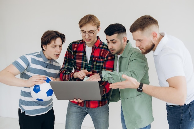 Group of guys male friends looking at sports betting coupon on\
laptop decide which team to bet on gambling concept sports betting\
online betting