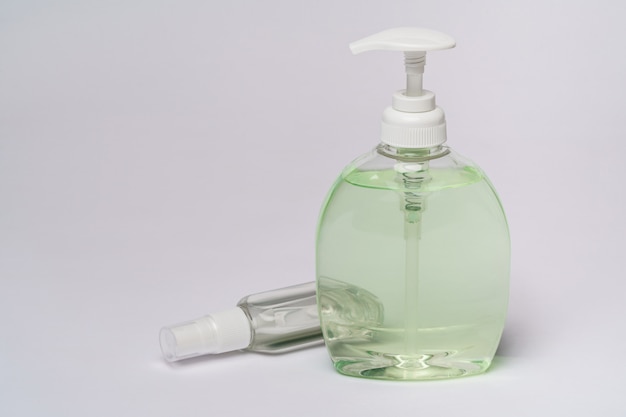 group of hand sanitizer spray or liquid soap bottles over light grey table