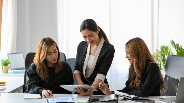 Un gruppo di donne d'affari asiatiche felici che lavorano insieme alla presentazione del loro progetto in ufficio.