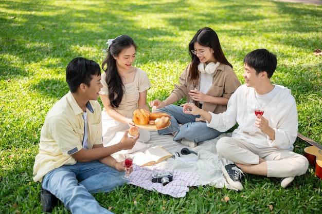 A group of a happy Asian friends is enjoying a picnic in a green park on a summer day together
