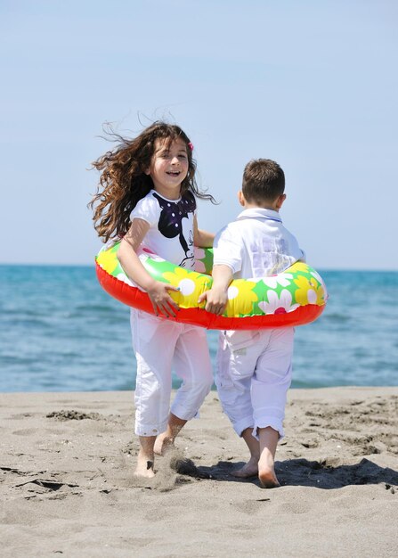 Gruppo di bambini felici sulla spiaggia che si divertono e giocano