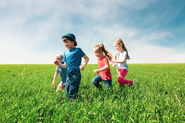 A group of happy children of boys and girls run in the Park on the grass on a Sunny summer day  The concept of ethnic friendship peace kindness childhood