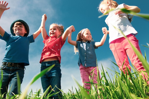 Un gruppo di bambini felici di ragazzi e ragazze corrono nel parco sull'erba in una soleggiata giornata estiva il concetto di amicizia etnica pace gentilezza infanzia