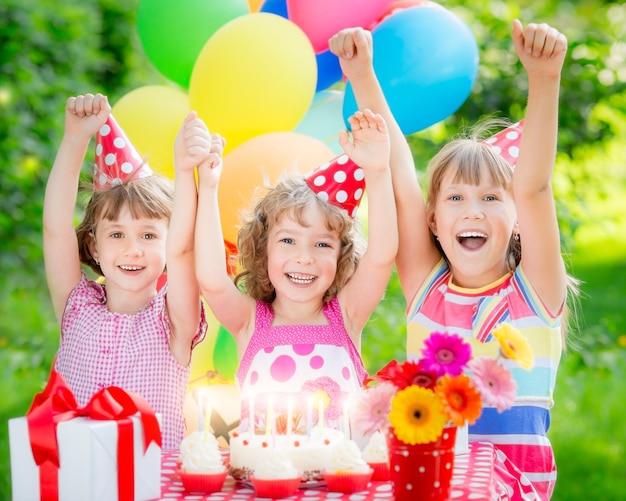 Foto gruppo di bambini felici che festeggiano il compleanno bambini che si divertono nel giardino di primavera