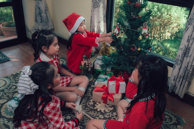 Un gruppo di bambini felici aiuta a decorare l'albero di natale per il periodo nataliziobuon natale e buone vacanze