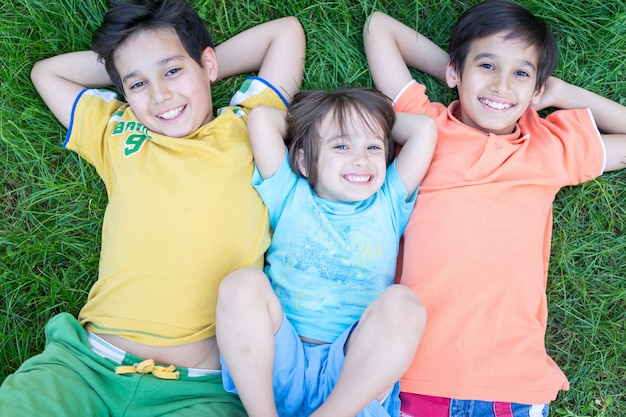 Photo group of happy children in summer lying on green grass