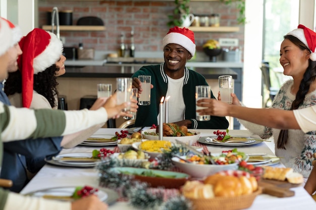 Group of happy diverse female and male friends toasting, celebrating christmas at home