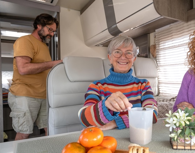 Group of happy family or friends stay together inside a camper van motor home at the coffee break Smiling people enjoying moment of relax Lifestyle vacation freedom journey modern people concept