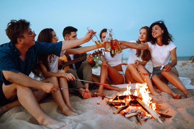 Group of happy friends cheers and drink beers on the beach enjoying vacation Vacation time laughing