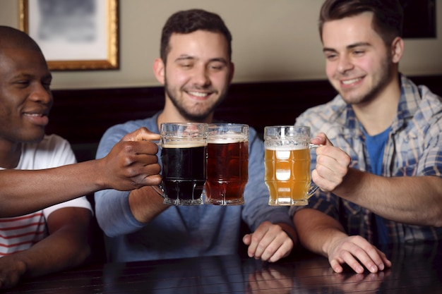 Group of happy friends drinking beer in pub