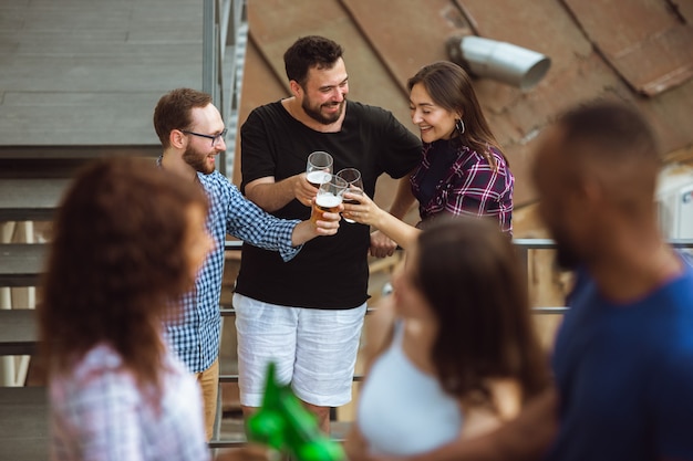 Group of happy friends having beer party in summer day.