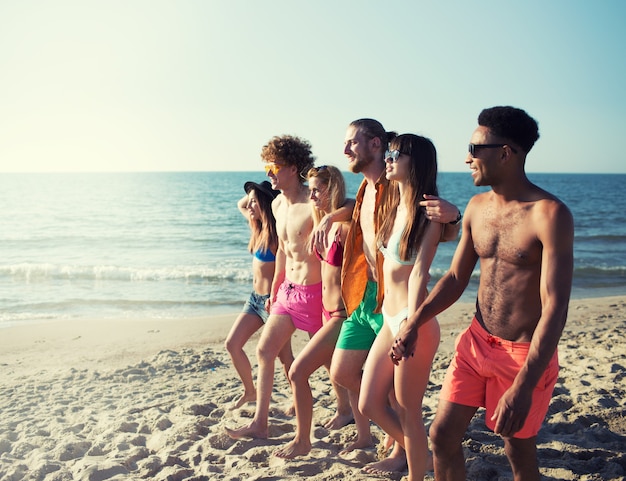 Group of happy friends having fun at ocean beach at dawn