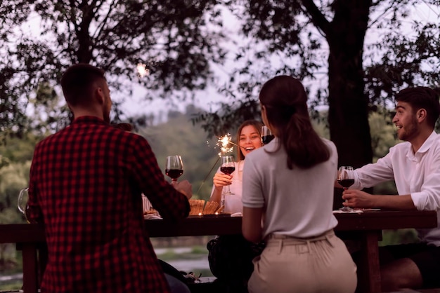 group of happy friends having picnic french dinner party outdoor during summer holiday vacation near the river at beautiful nature