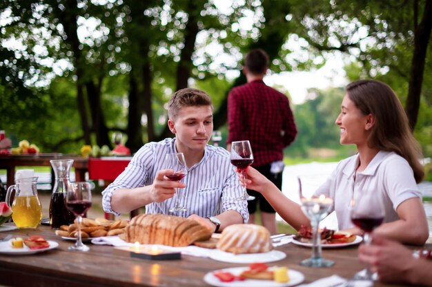 group of happy friends having picnic french dinner party outdoor during summer holiday vacation  near the river at beautiful nature