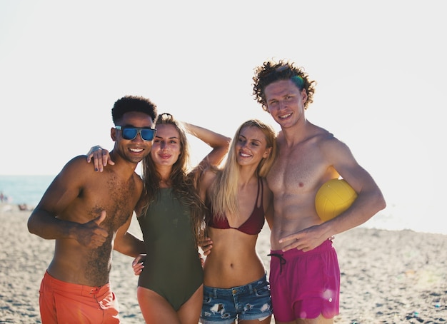 Group of happy friends playing at beach volley at the beach