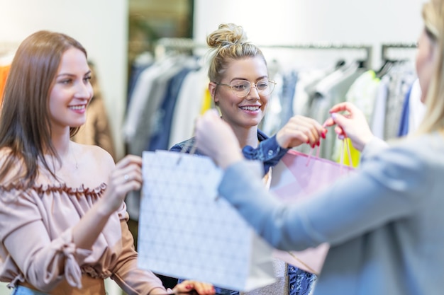 group of happy friends shopping for clothes in mall