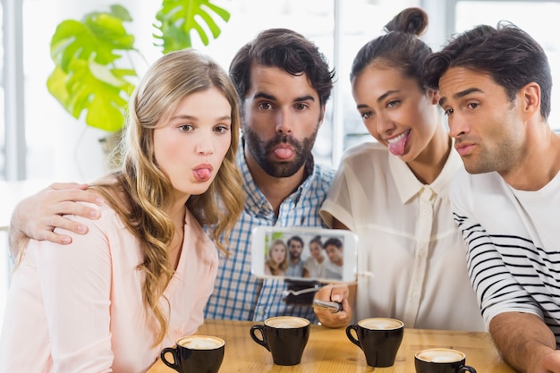 Group of happy friends taking picture with slefie stick