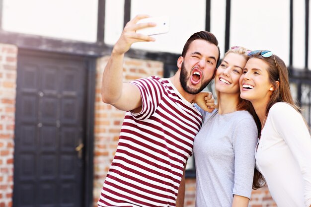 group of happy friends taking selfie in the city