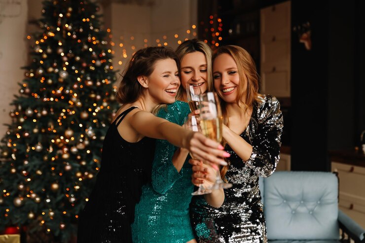 Photo a group of happy friends of women hold glasses drink champagne dance celebrate the christmas holiday