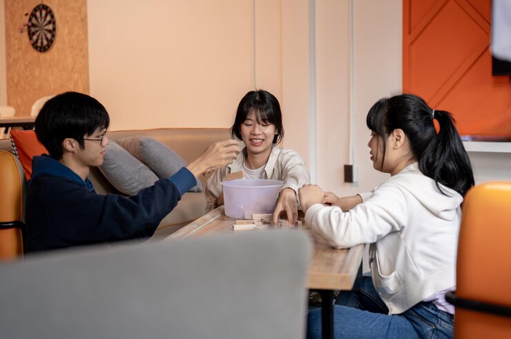 Photo 幸せで楽しいアジア人友達のグループが家で一緒にjengaゲームを楽しんでいます