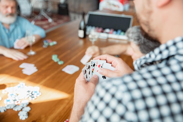 Group of happy mature friends playing cards