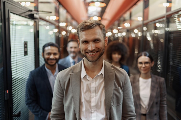 Group of happy motivated business people standing together at office with their leader