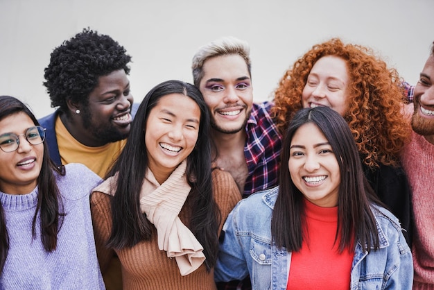 Group of happy multiethnic people hugging each other outdoor while smiling on camera