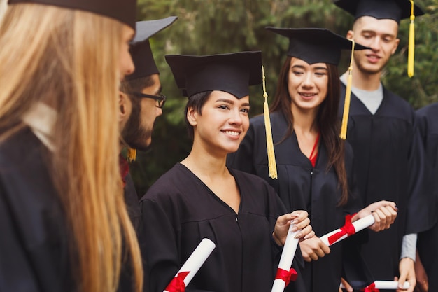 Group of happy multiethnic students on graduation day, having fun. Happy people celebrating education degree, copy space