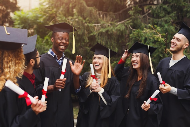 Group of happy multiethnic students on graduation day, having fun. Happy people celebrating education degree, copy space