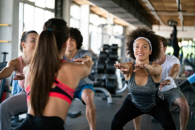 Group of happy multiracial friends exercising together in gym