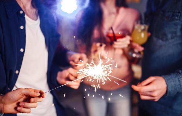 Group of happy people holding sparklers at party and smiling.