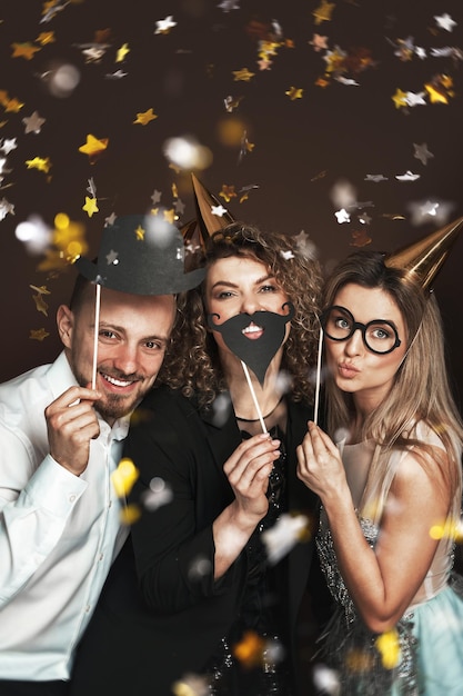 Photo group of happy people wearing party hats and using funny photo booth props are celebrating a holiday or event