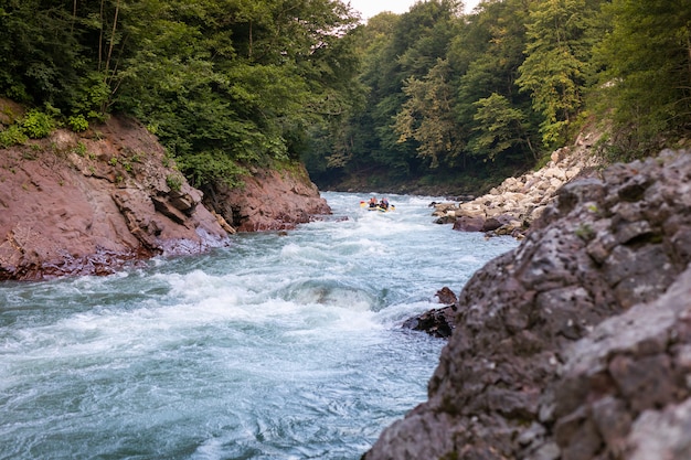 Group of happy people with guide whitewater rafting and rowing on river. 