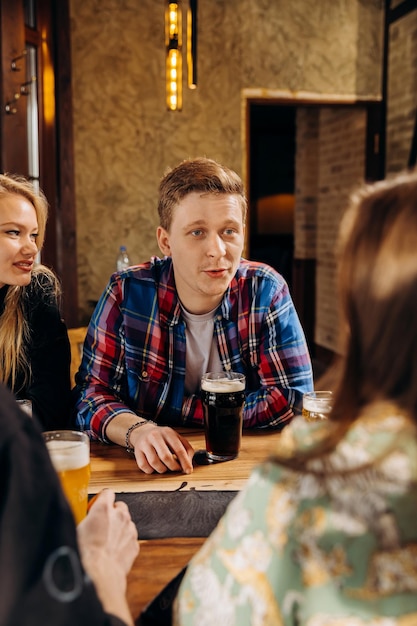 Group of happy relaxing friends drinking beer and coctails and having talk in pub restaurant Celebration and party concept