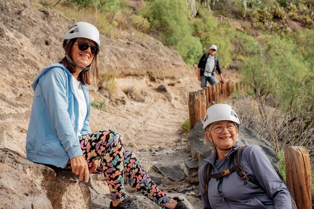 Group of happy senior people enjoying a trekking day in mountain wearing protective helmets